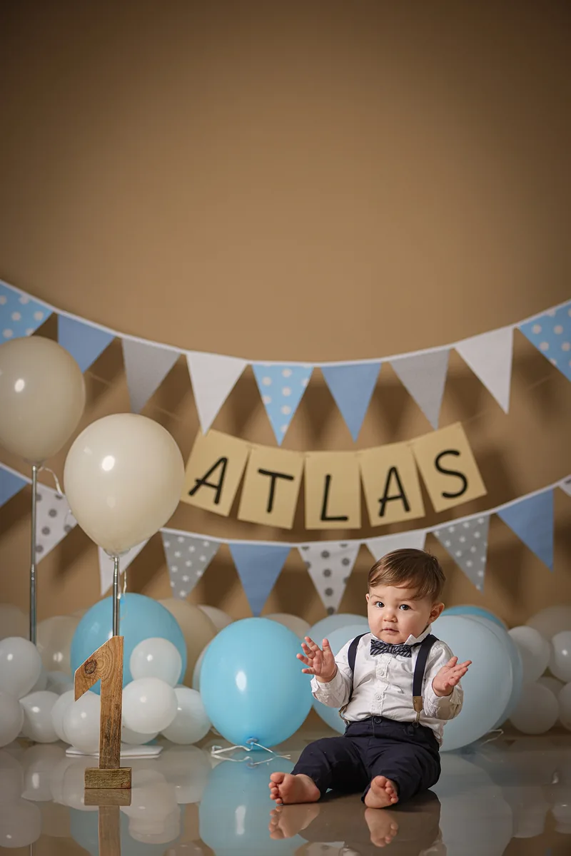 Kleinkind unter einer Wimpelkette mit dem Namen Atlas – Kindergeburtstag im Studio