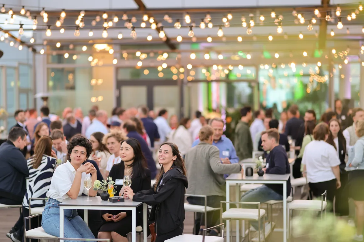 Gäste an Bistrotischen unter Lichterketten – Firmenevent in Berlin